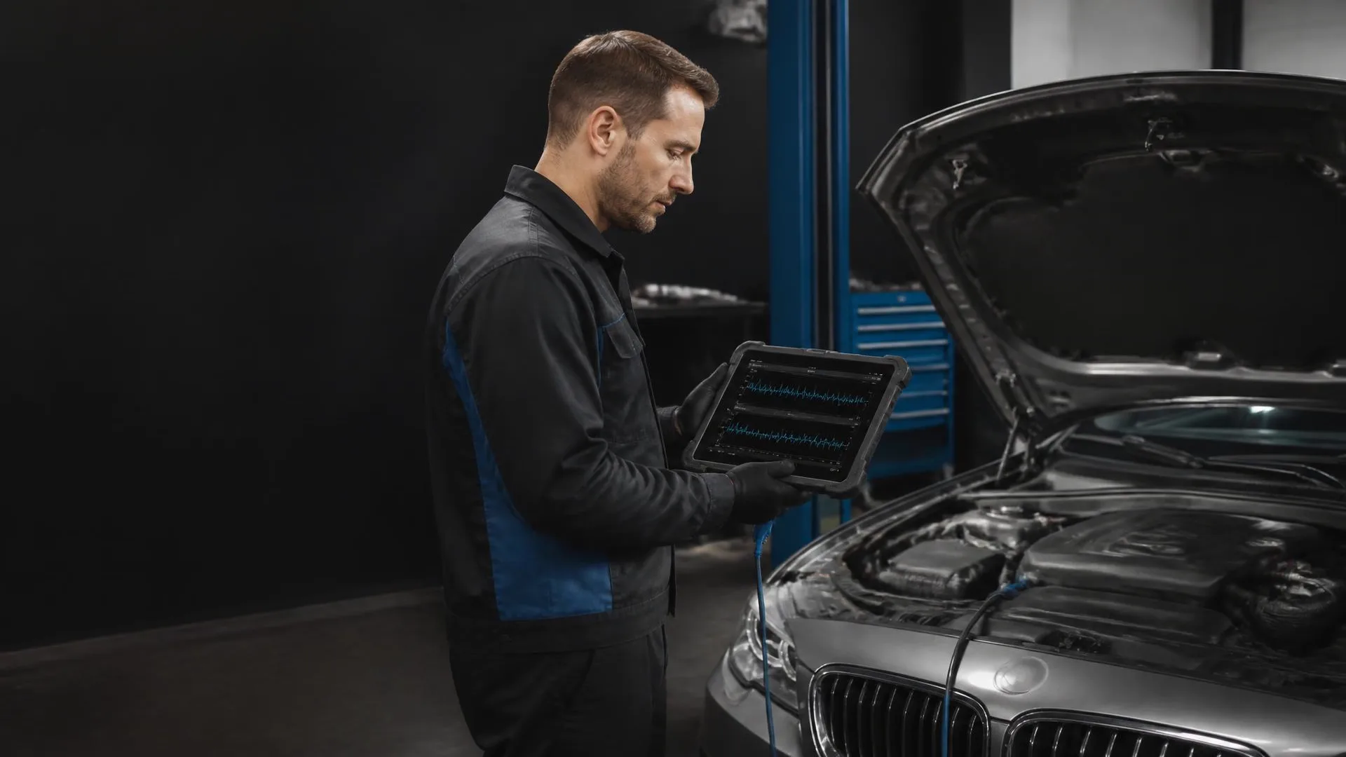 Technician reading live diagnostic data on a professional scan tablet beside an open European engine bay